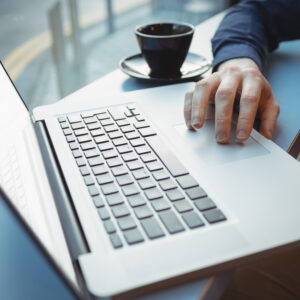 Mid-section of male executive using laptop in cafeteria
